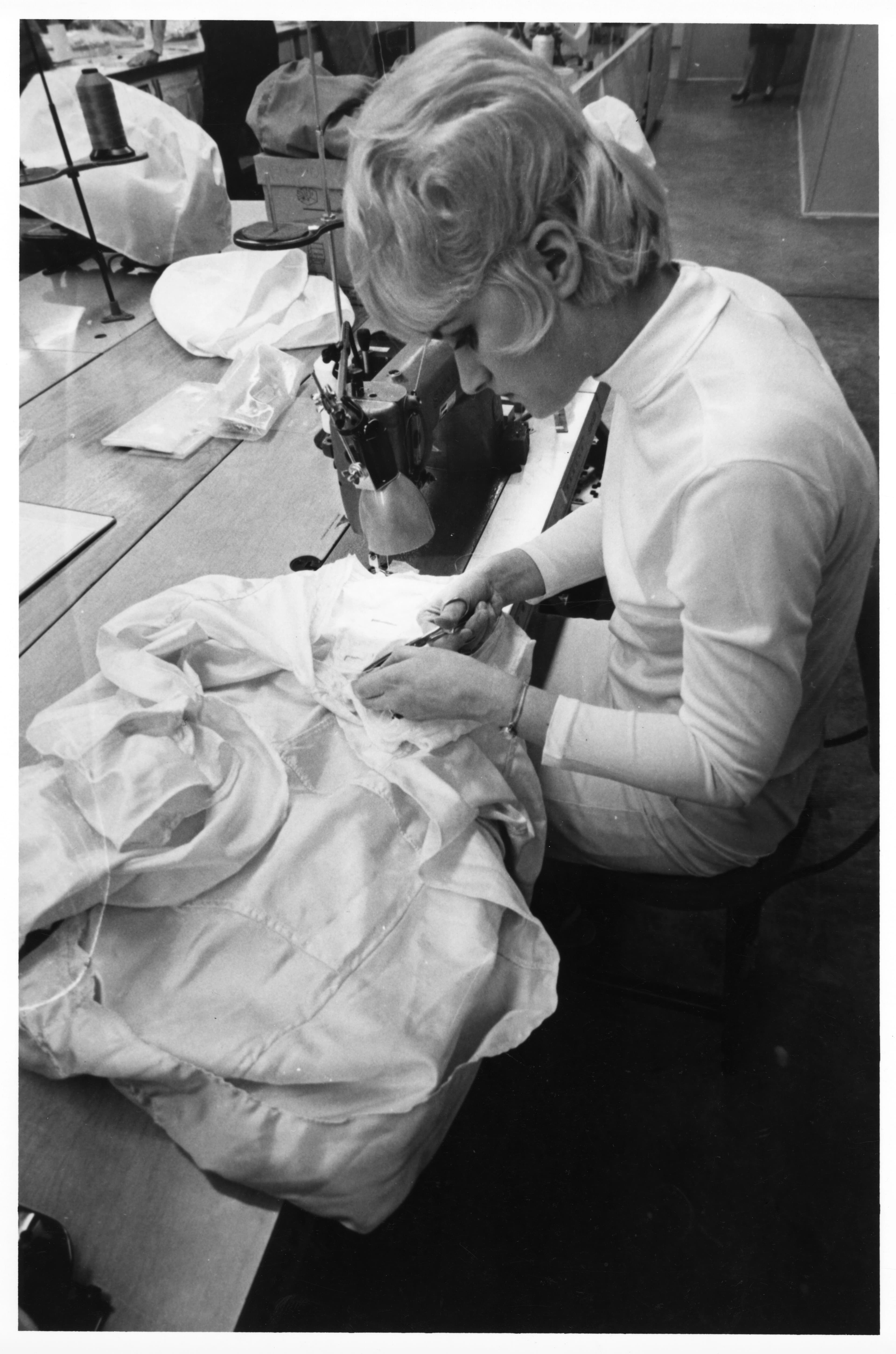 Close up black and white profile shot of an International Latex Corporation (ILC) seamstress working on an Apollo spacesuit.