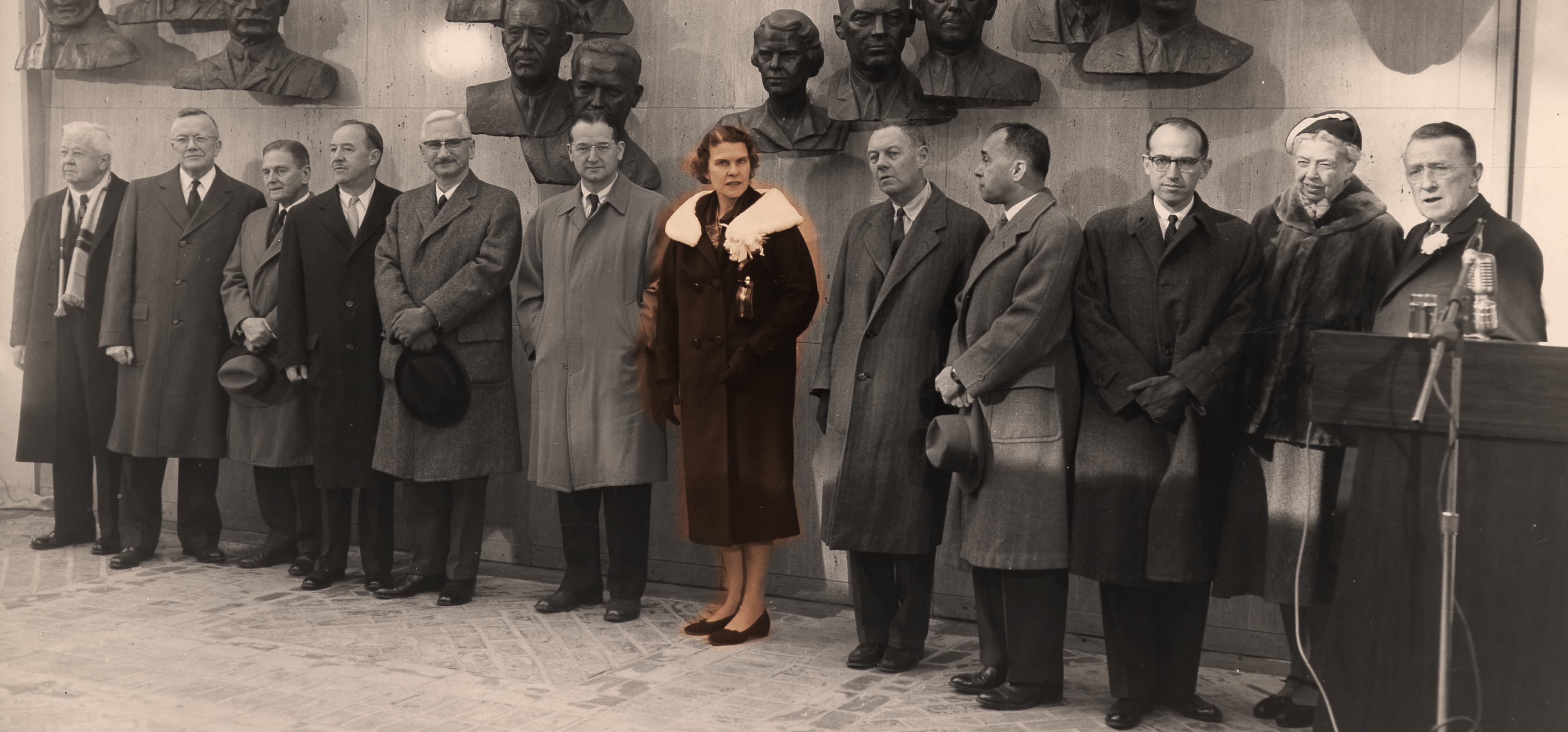 Black and white photo of a group of scientists standing behind a podium with Isabel Morgan in the middle. She is one of two women in the group.